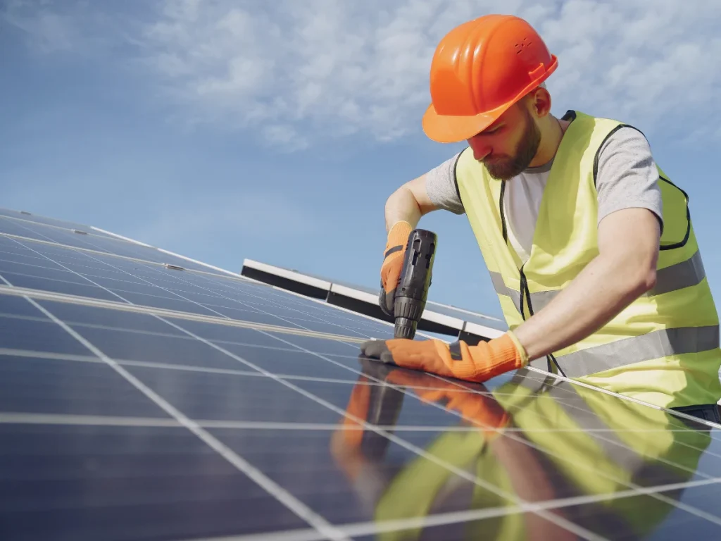 Solar installer in a hard hat fitting a panel on a roof