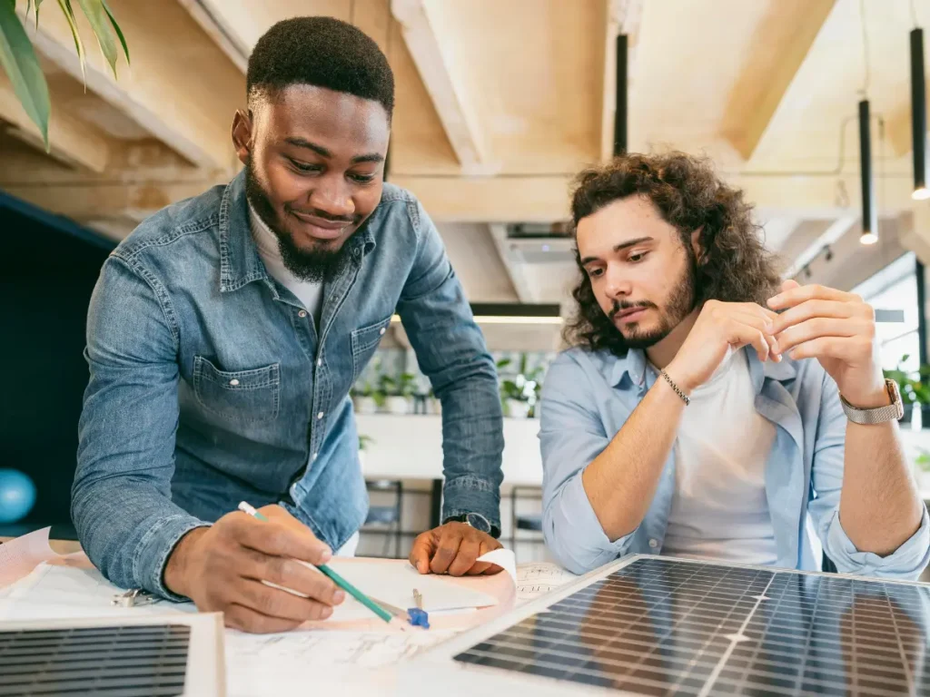 Two people planning a solar system over drawings and a solar panel